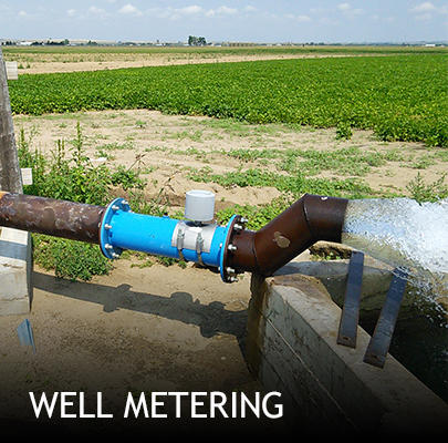 A well meter and outlet pipe showing water under high pressure exiting onto the grass